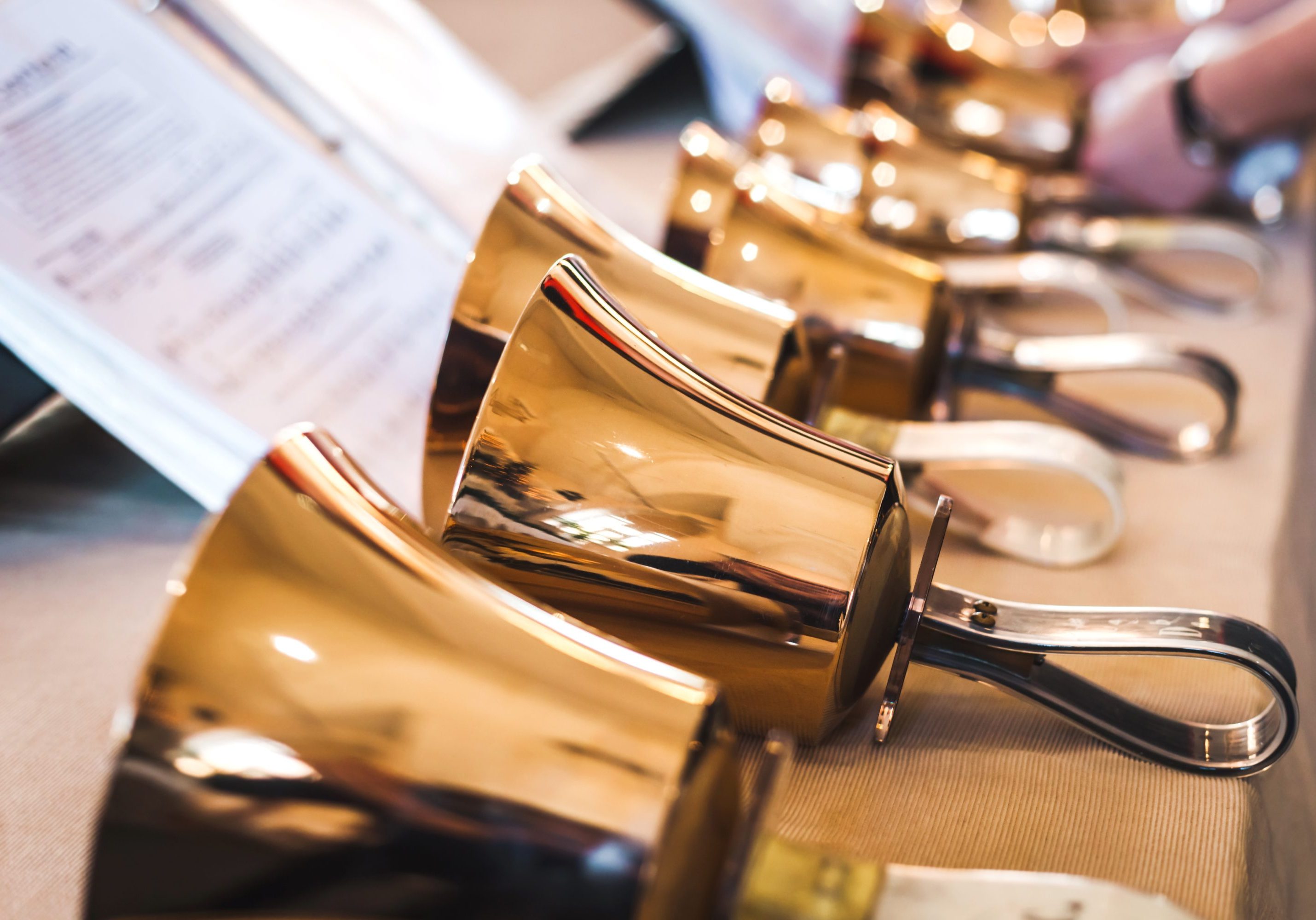 Golden handbells on table with sheet of notes